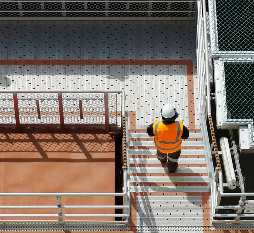 An engineer walking down some stairs on a platform, viewed from above